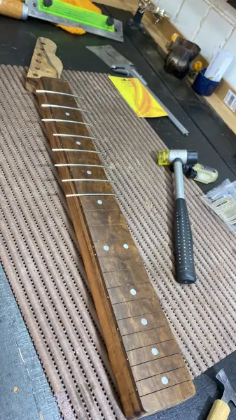 Instalação de trastes em braço de guitarra com martelo de luthier