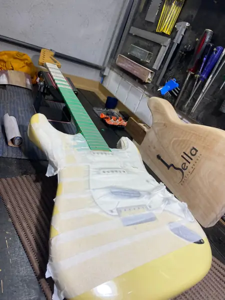 Guitarra estilo Stratocaster creme em regulagem na bancada