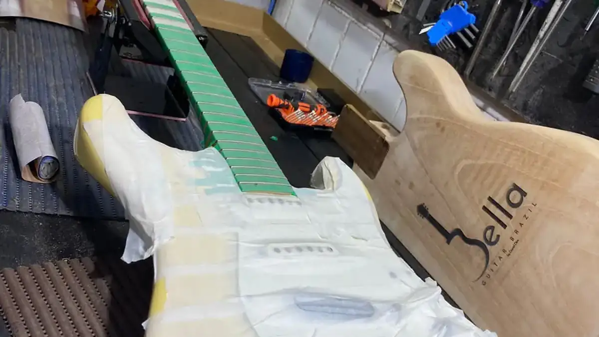 Guitarra estilo Stratocaster creme em regulagem na bancada